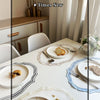 A close-up of a white ceramic plate with bread on it set on a table, emphasizing high quality fabric.