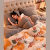 A woman relaxing on a plush, double-sided fleece blanket with a quilted pattern and soft gray and orange tones.