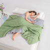 A woman is relaxing on a white surface covered with a green quilted blanket.