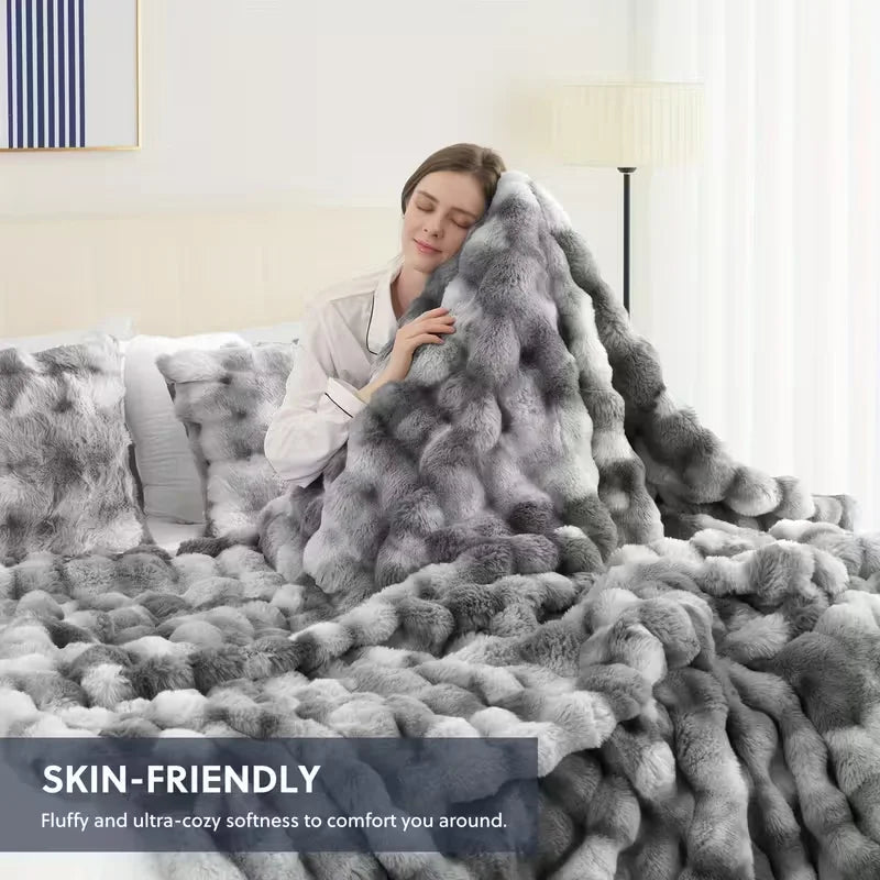 A person is resting their head on a fluffy gray faux fur rabbit blanket in a bright bedroom setting.