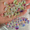 A hand holds a cluster of clear and colored crystal glass beads with two-hole designs for jewelry making