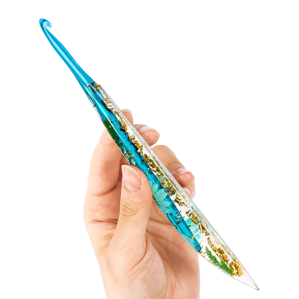 A hand holds a floral patterned epoxy crochet hook set with a blue handle and clear shaft.