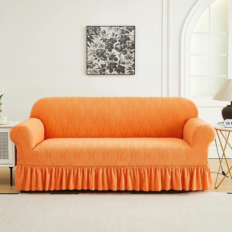 An orange sofa cover with a ruffled bottom sits on a light rug in a well-lit room.