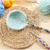 Handmade crochet knitting hooks and a light blue crocheted bowl resting on a woven mat.