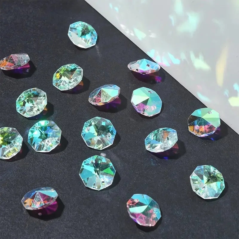 A collection of faceted crystal glass beads in various shades of blue and green scattered on a dark surface.