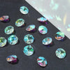 A collection of faceted crystal glass beads in various shades of blue and green scattered on a dark surface.