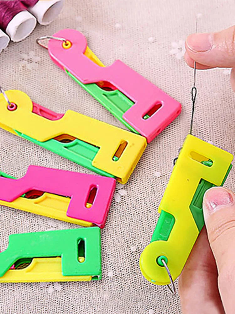 A collection of colorful automatic sewing needle threaders, including pink, yellow, and green plastic tools.