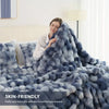 A fluffy blue faux fur rabbit blanket draped over a person in a bright bedroom setting.