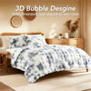 A fluffy gray and white faux fur bubble blanket is displayed on a bed, adding texture to a bedroom setting.