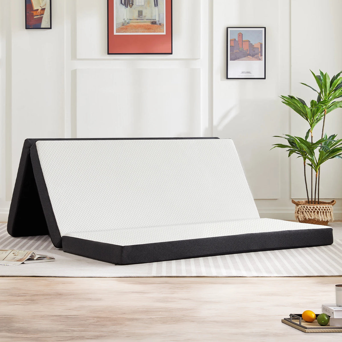 A tri-fold memory foam mattress is shown unfolded on a light wooden floor in a well-lit room.