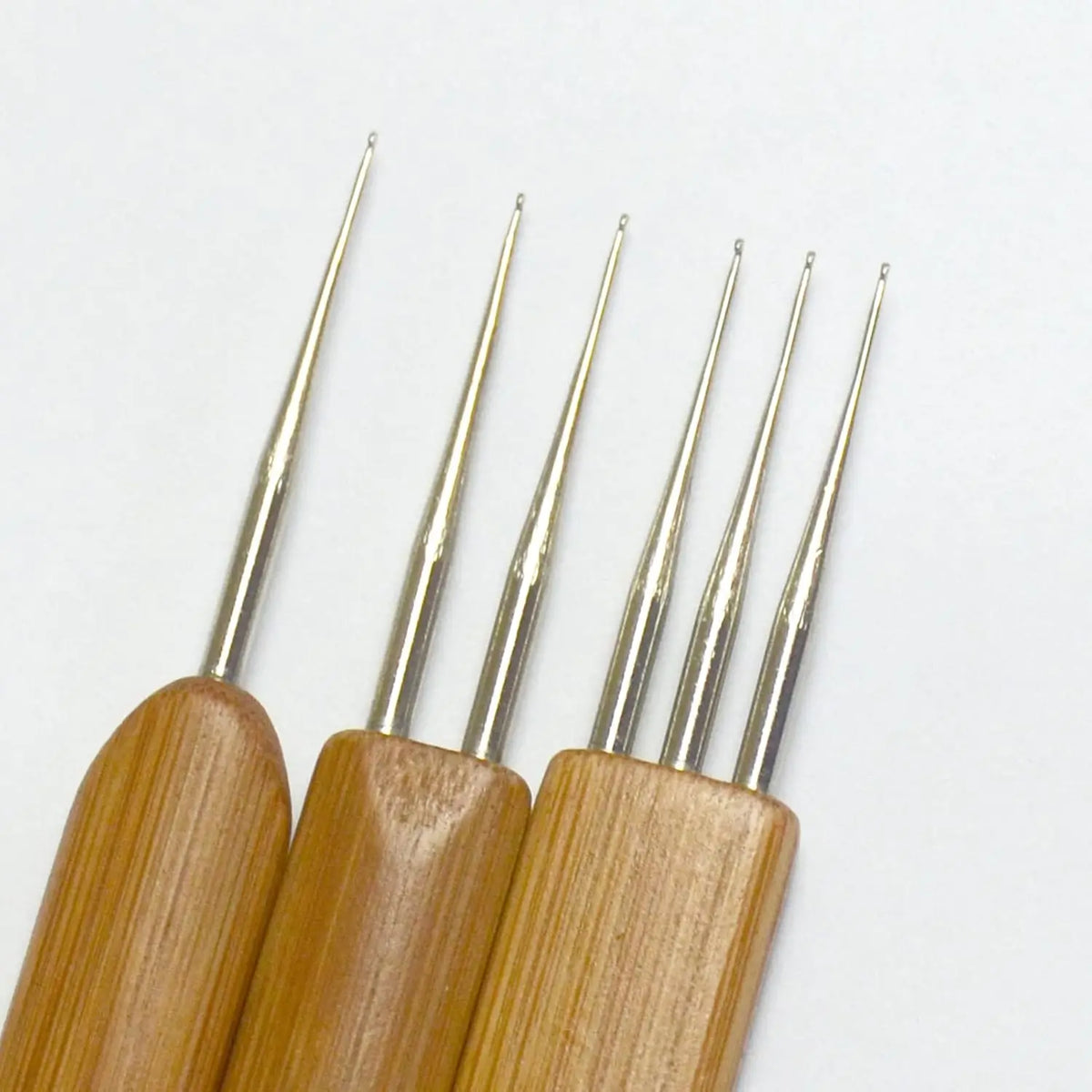 A set of wooden dreadlock crochet hooks with silver tips arranged in a row.