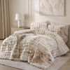 A large, fluffy cream faux fur blanket with a textured surface is displayed on a bed.