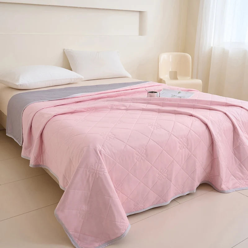 A pink quilted blanket is draped over a bed in a bright room.