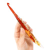 A hand holds an orange and gold floral patterned epoxy crochet hook set.