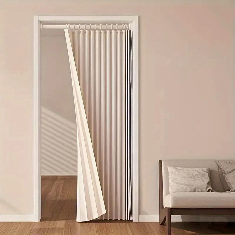 A folding privacy curtain in beige and black stripes is shown hanging in a white door frame.