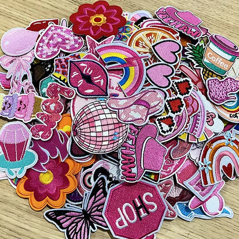 A collection of pink and purple embroidered cartoon iron-on patches featuring various shapes and designs.