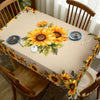 A dining table set with a beige tablecloth featuring a large sunflower floral design and matching place settings.