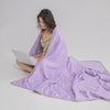 A person is wrapped in a purple quilted blanket, suggesting a cooling breathable blanket for hot sleepers.