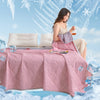 A woman is relaxing on a pink cooling blanket surrounded by ice cubes and snowflakes.