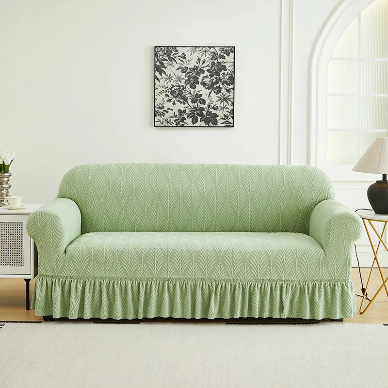 A light sage green sofa cover with a textured fabric sits on a white rug in a bright room.