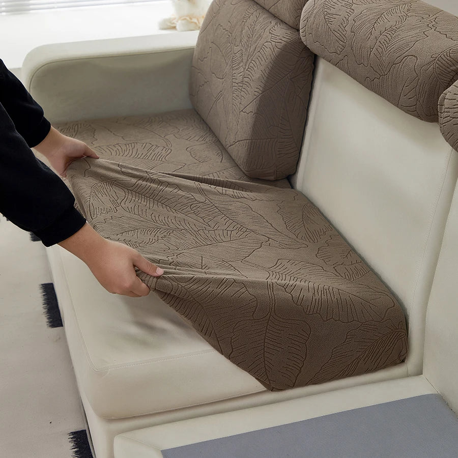 A close-up of a brown jacquard elastic sofa cushion cover protecting a light-colored sofa cushion.