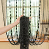 A hand is holding a black beaded string curtain for doorways or weddings.