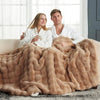 A couple is relaxing together under a large, fluffy tan faux fur rabbit blanket.