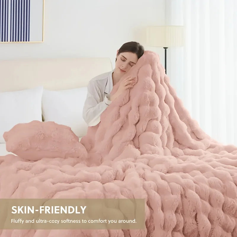 A pink faux fur rabbit blanket draped over a bed, showing its fluffy texture and cozy softness.