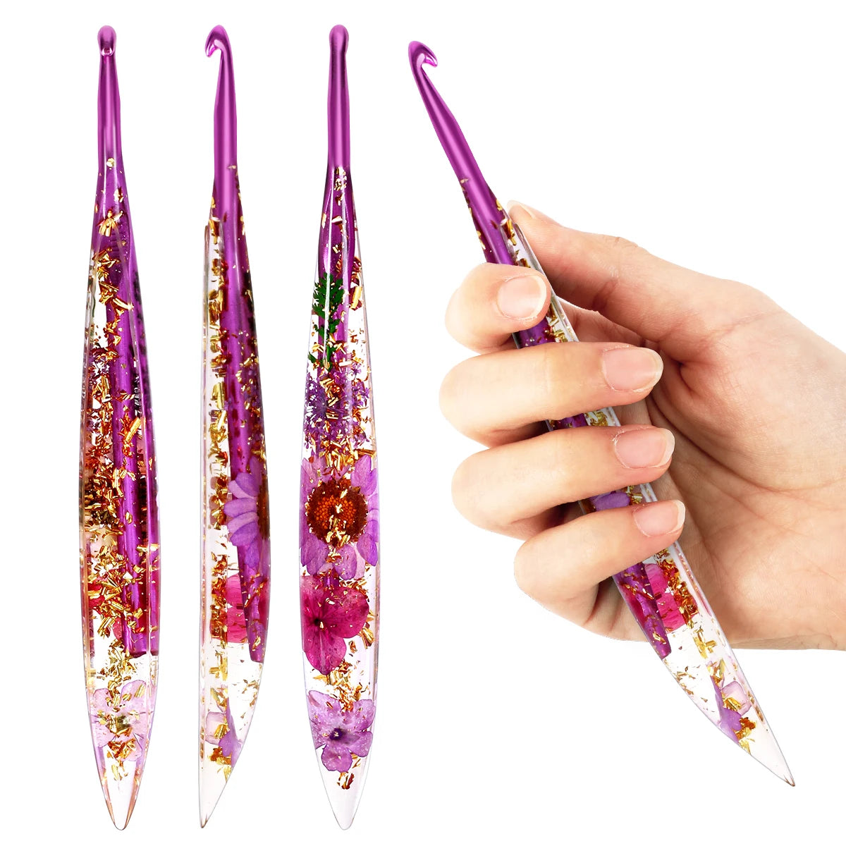 A hand holds a set of floral patterned epoxy crochet hooks with purple and pink accents.