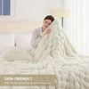 A fluffy white faux fur rabbit blanket draped over a bed, emphasizing softness and comfort.