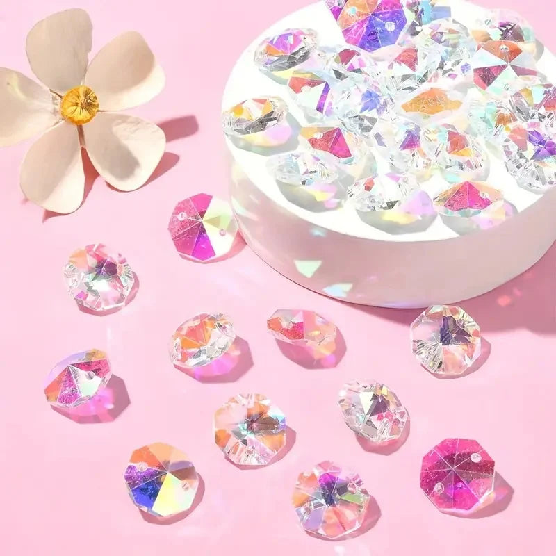 A collection of iridescent crystal glass beads in various colors scattered on a pink surface.