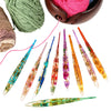 A set of floral patterned epoxy crochet hooks and yarn spools with pink, green, and orange colors.