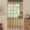 A window dressed with a minimalist beaded string curtain featuring black threads and a gold chandelier.