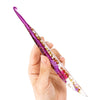 A hand holds a floral patterned epoxy crochet hook set with purple and gold accents.