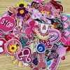 A collection of pink and purple embroidered cartoon iron-on patches featuring various shapes and designs.