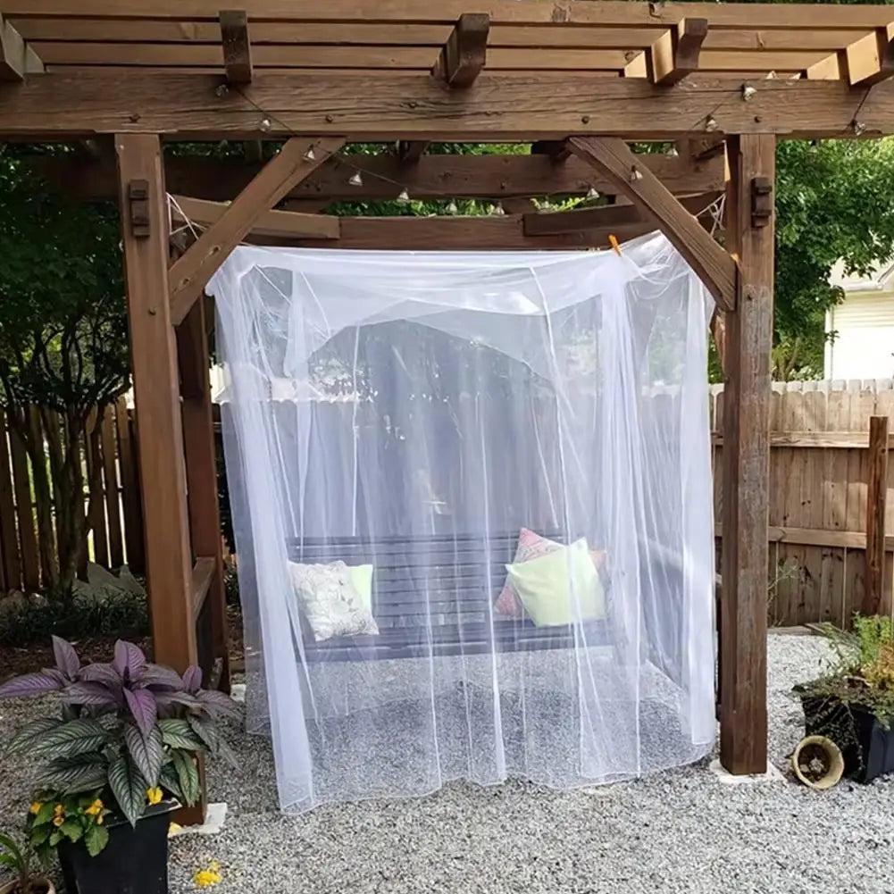 A large white mosquito net is draped over a wooden frame structure outdoors.