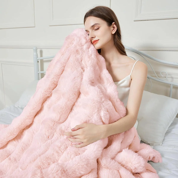 A woman is wrapped in a fluffy pink faux fur rabbit blanket lying on a white bed.