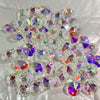 A pile of clear crystal glass beads with two-hole designs showing various iridescent colors.