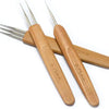 A set of wooden dreadlock crochet hooks with sharp metal tips.