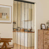 A vertical beaded string curtain covering a doorway, featuring beige and black threads.