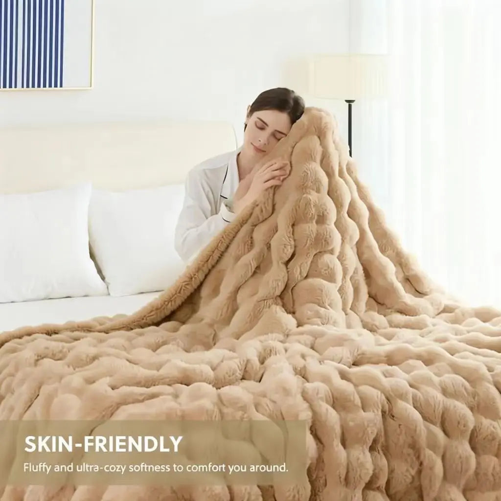 A fluffy, light brown faux fur rabbit blanket draped over a bed.
