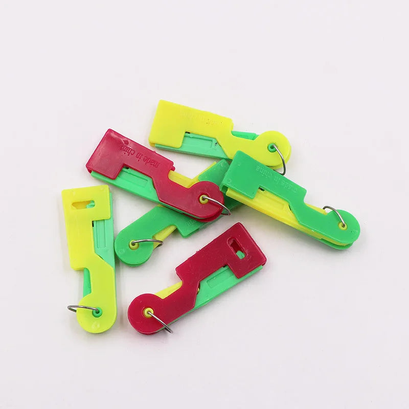 A set of five automatic sewing needle threaders in various colors including red, green, and yellow.