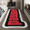 A black and red letter doormat with the word WASTED in large block letters placed on a wooden floor.