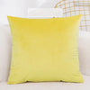A bright yellow velvet decorative cushion cover resting on a white surface.