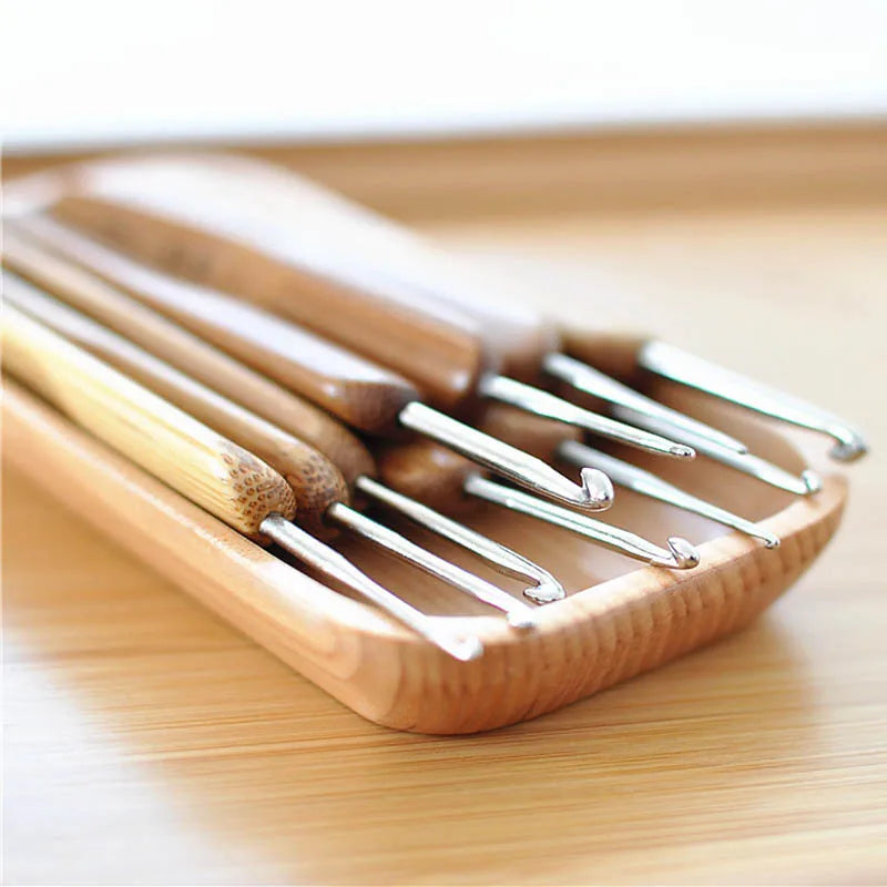 A set of wooden bamboo crochet knitting needles lying on a light wooden surface.