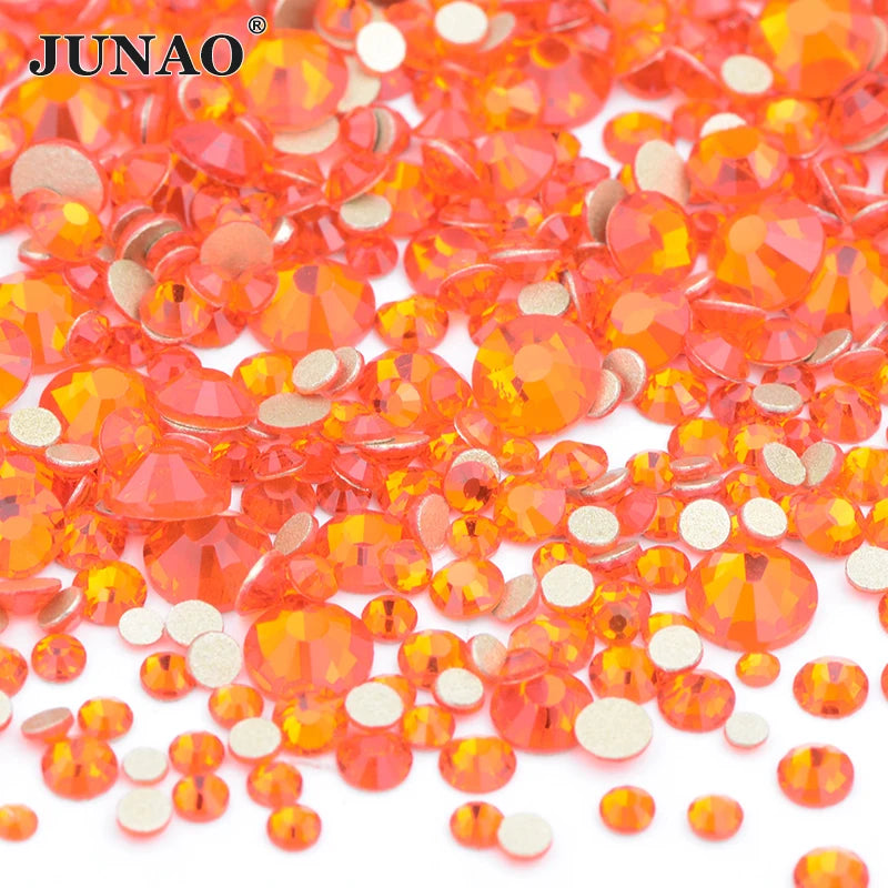 A pile of small, round, clear glass orange and pink rhinestones for DIY crafts.