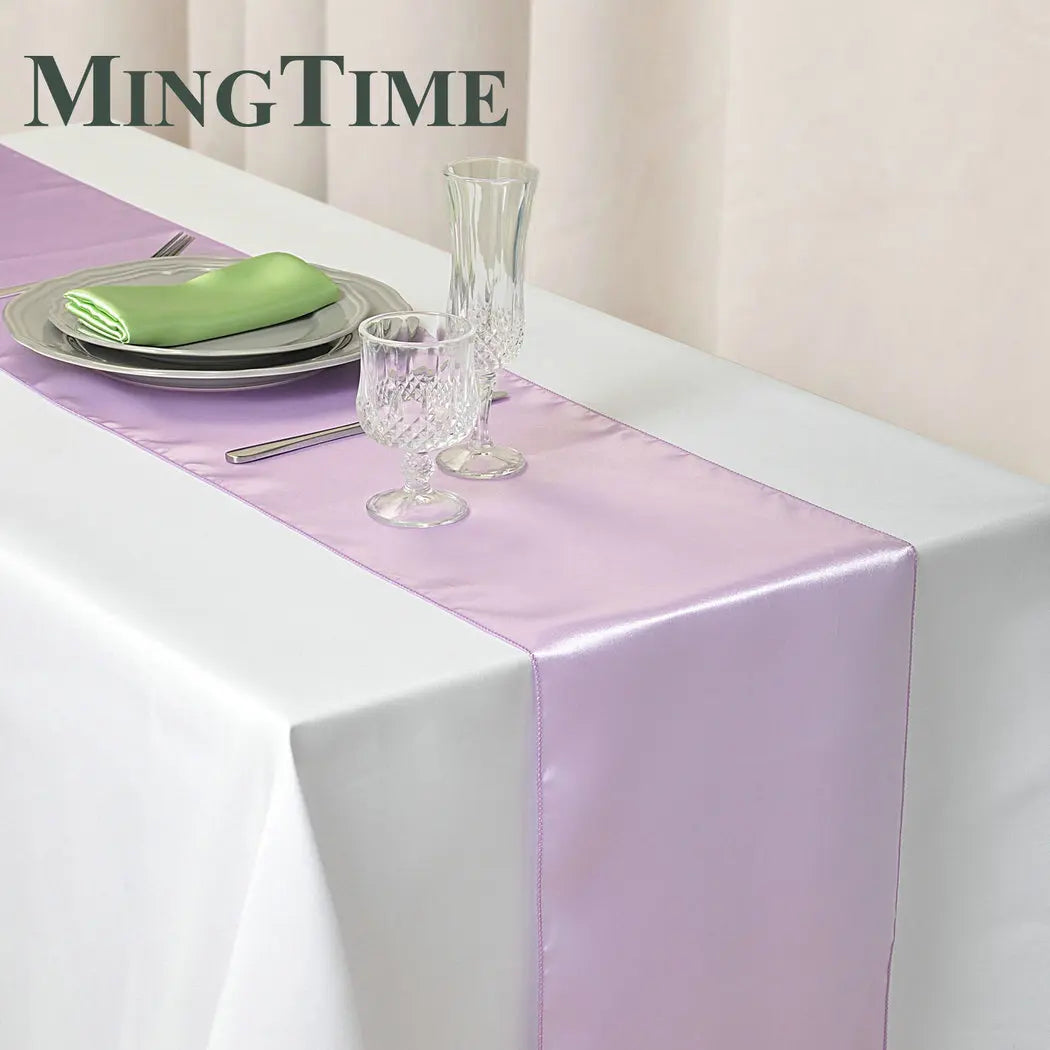Elegant purple satin table runner displayed on a white tablecloth with silverware and glassware.