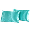 A pair of teal silky satin pillowcases lying next to each other.