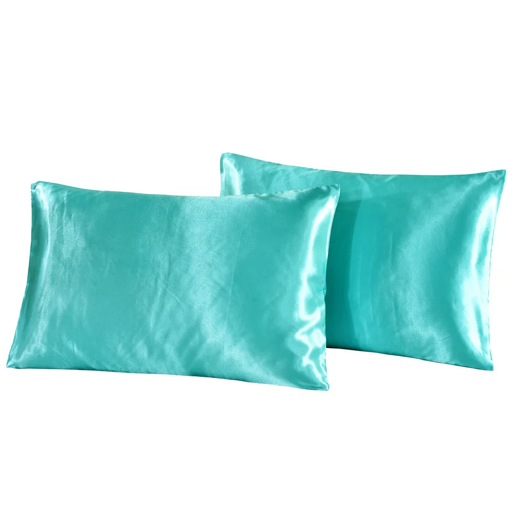 A pair of teal silky satin pillowcases lying next to each other.