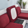 A deep red stretch sofa seat cushion protector slipcover with a white interior and black protective pad.